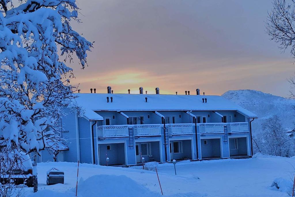 a building with snow on the roof of it at Panorama Blue Apartments in Kilpisjärvi