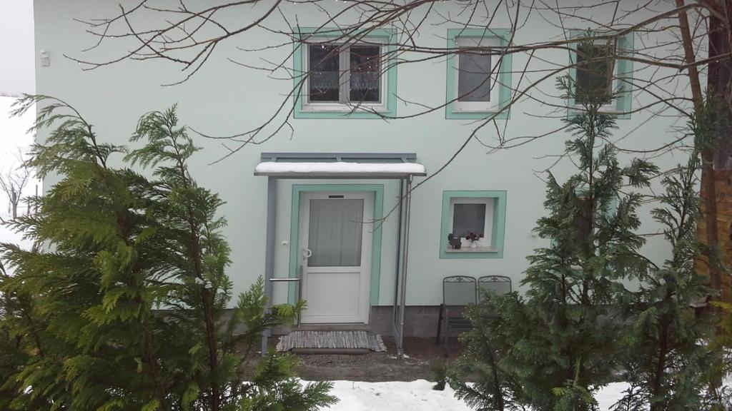 a white house with a blue door and trees at Haus Alpenhof in Immenstadt im Allgäu
