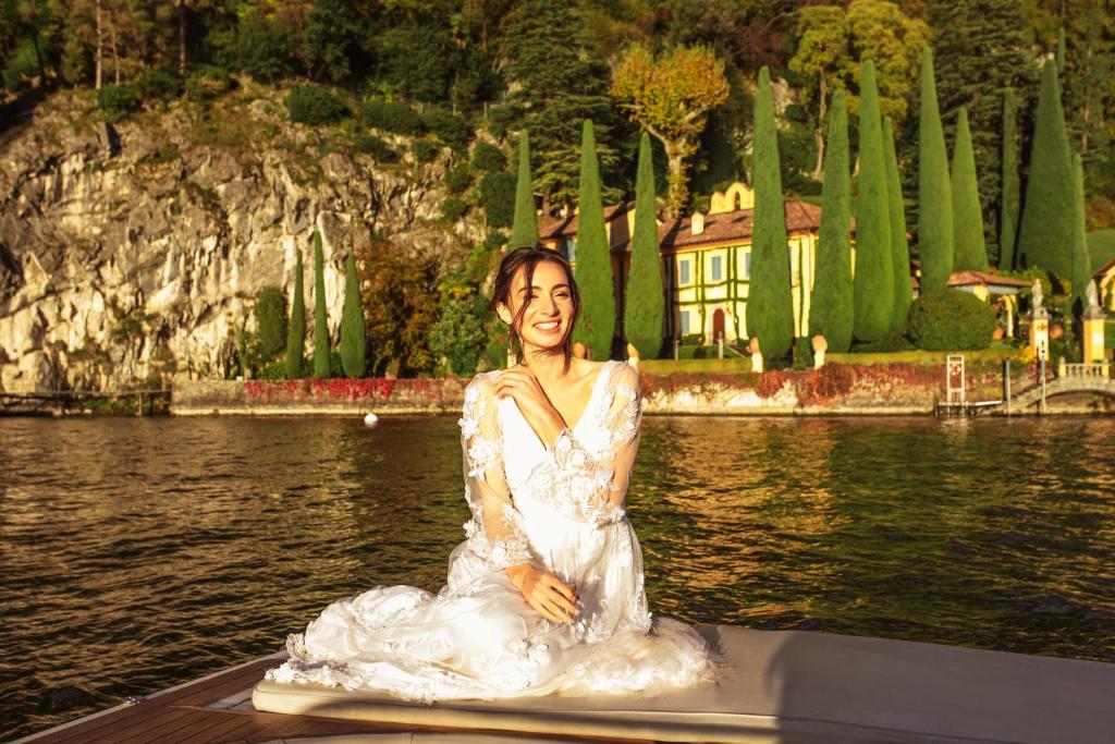 una mujer con un vestido blanco sentada en la parte trasera de un barco en Villa Oleandra nearby Argegno with privet Garden & Pool, en Dizzasco