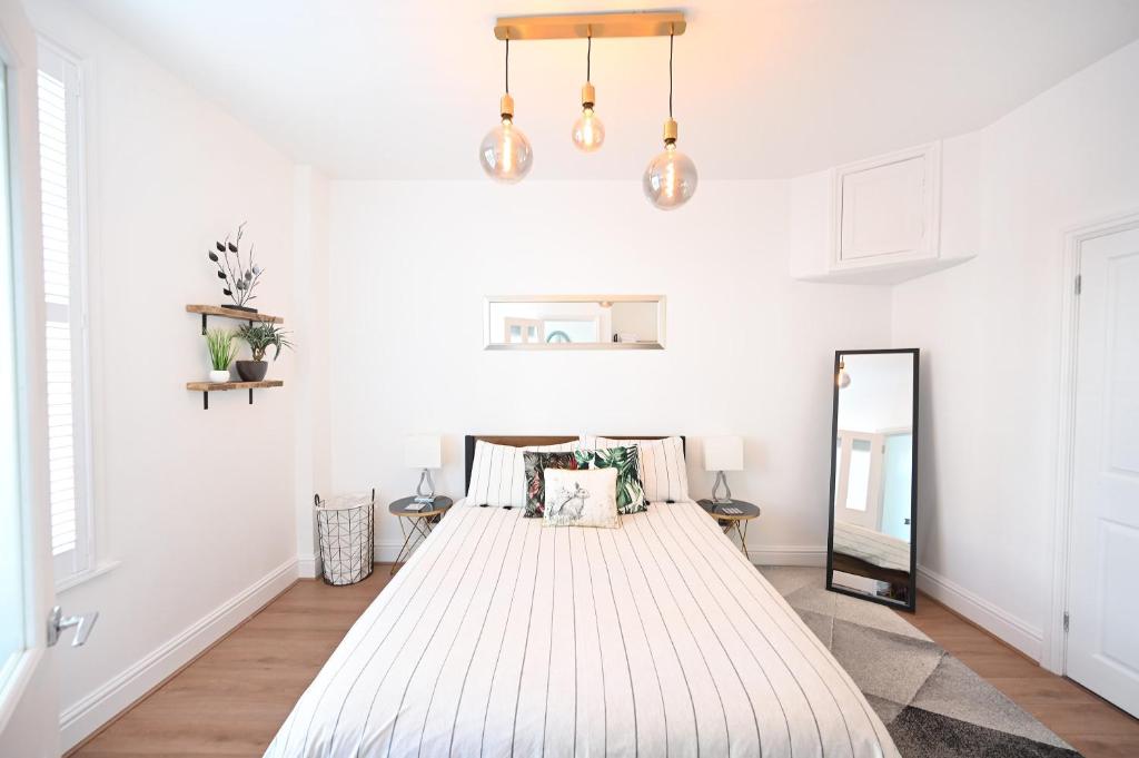 1 dormitorio con 1 cama blanca grande y espejo en The Teapot Cottage in town centre FREE parking, en Stratford-upon-Avon