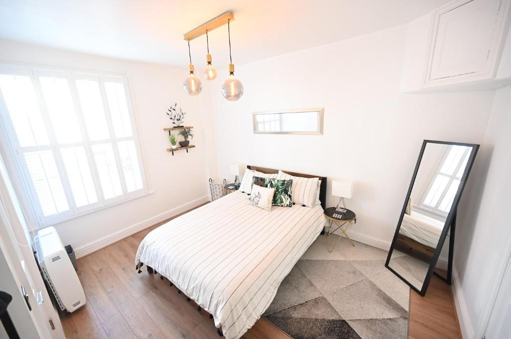 a white bedroom with a bed and a mirror at The Teapot Cottage in Town Centre FREE Parking in Stratford-upon-Avon