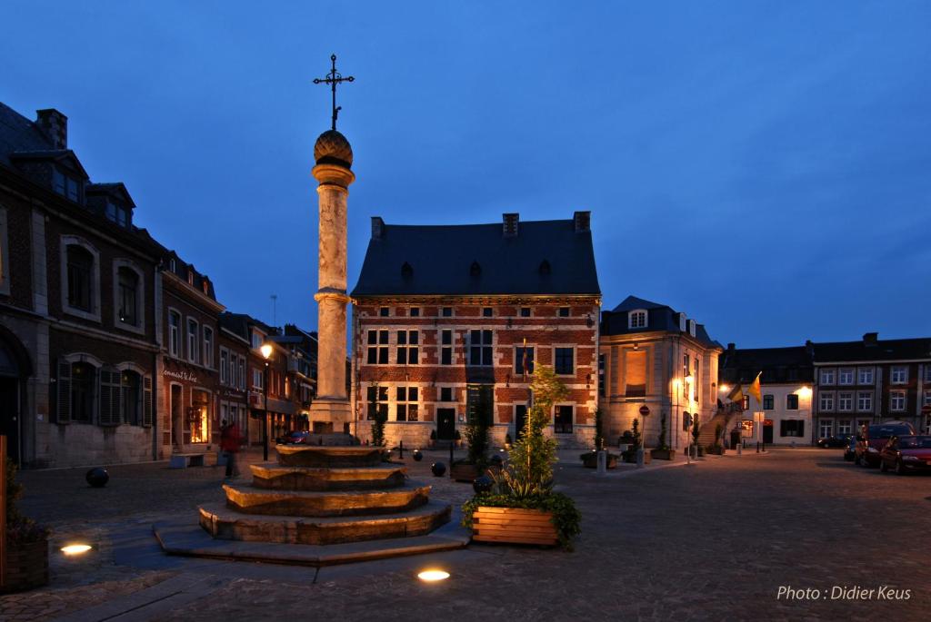 a building with a clock tower in the middle of a street at Hôtel du Perron in Theux