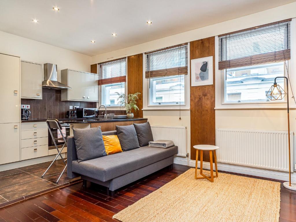 Il comprend un salon avec un canapé et une cuisine. dans l'établissement Pass the Keys Beautiful Museum Street Apartment, à Londres