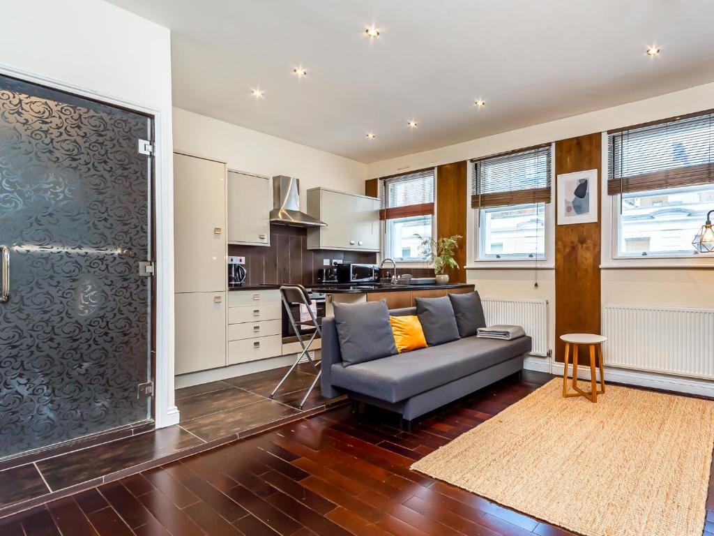 Pass the Keys West End Apartment near Tottenham Court Road في لندن: غرفة معيشة مع أريكة ومطبخ