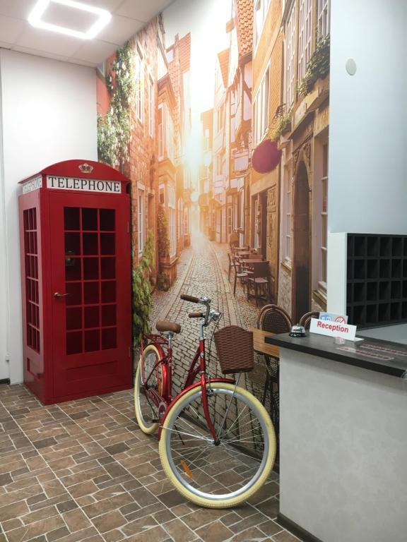 a red phone booth and a bike parked on a street at Hotel Rover in Lviv