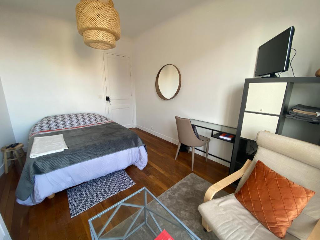 a bedroom with a bed and a desk and a mirror at Grande chambre privative à 20 minutes de Paris in Colombes