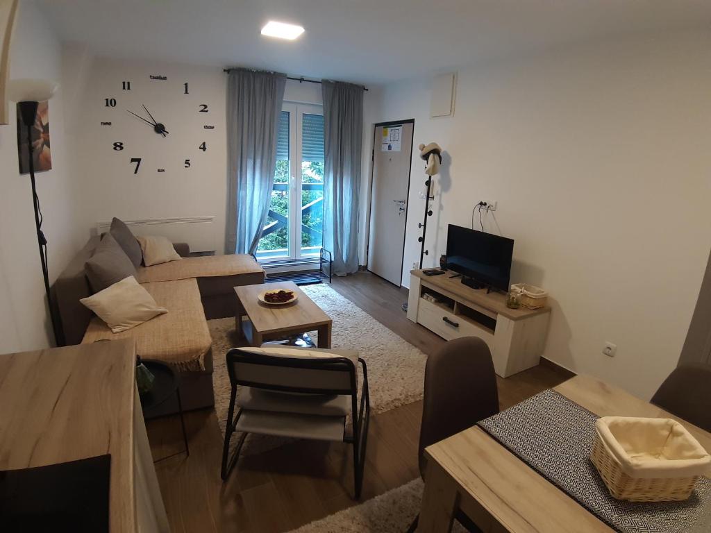 - un salon avec un canapé et un réveil sur le mur dans l'établissement Ajrin Apartman Kopaonik, à Kopaonik