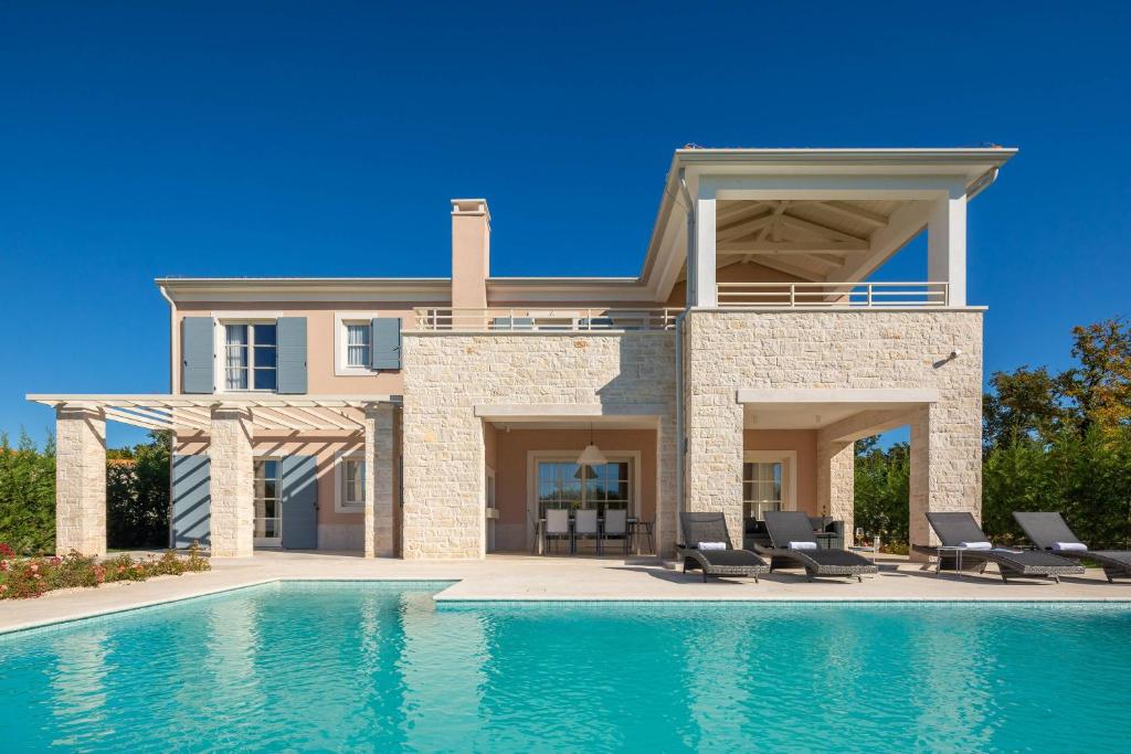 a house with a swimming pool in front of a house at Villa Divine by ILC (Istria Luxury Collection) in Brtonigla
