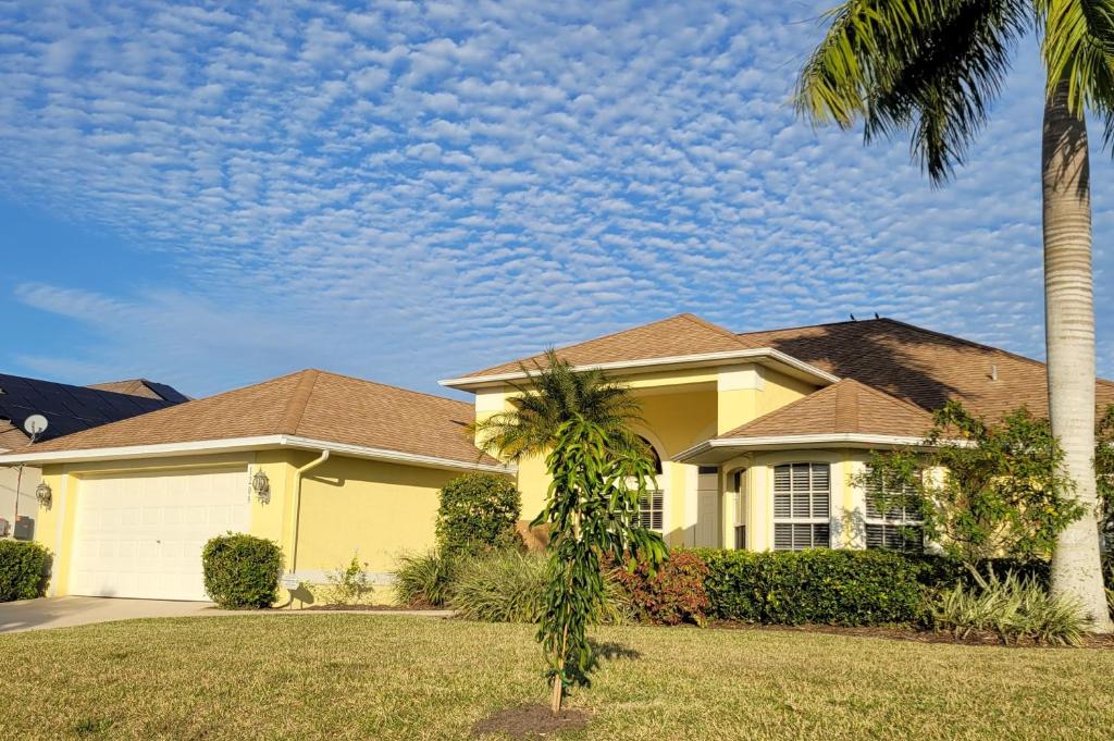 a yellow house with a palm tree in a yard at Villa Tortuga - Place to Relax in Cape Coral