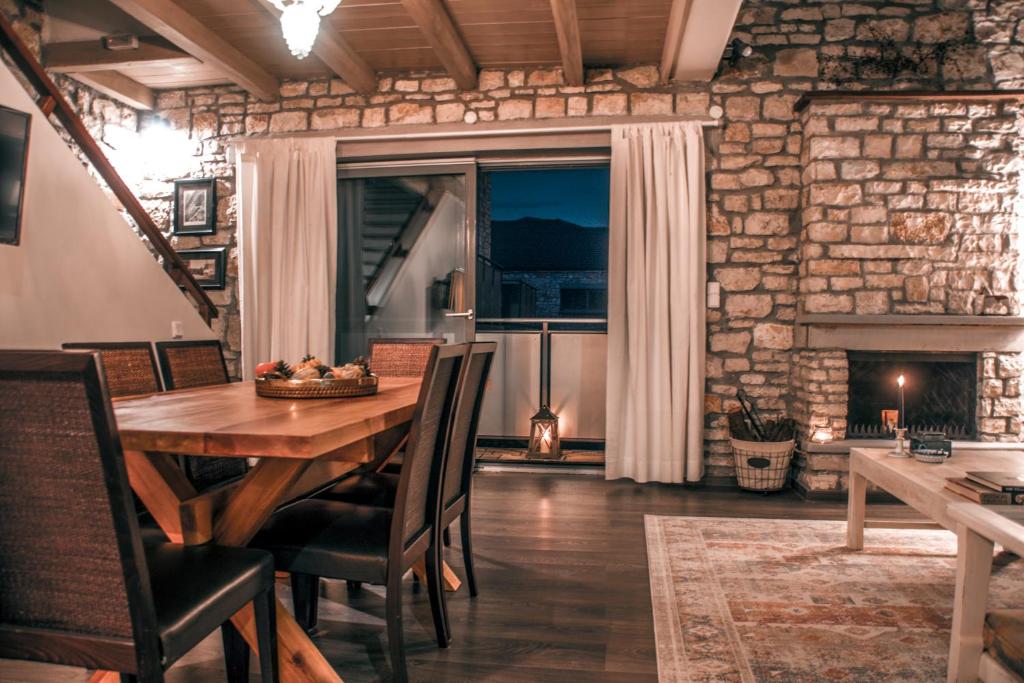 a dining room with a wooden table and a fireplace at Epirus Stone Suites in Elaía