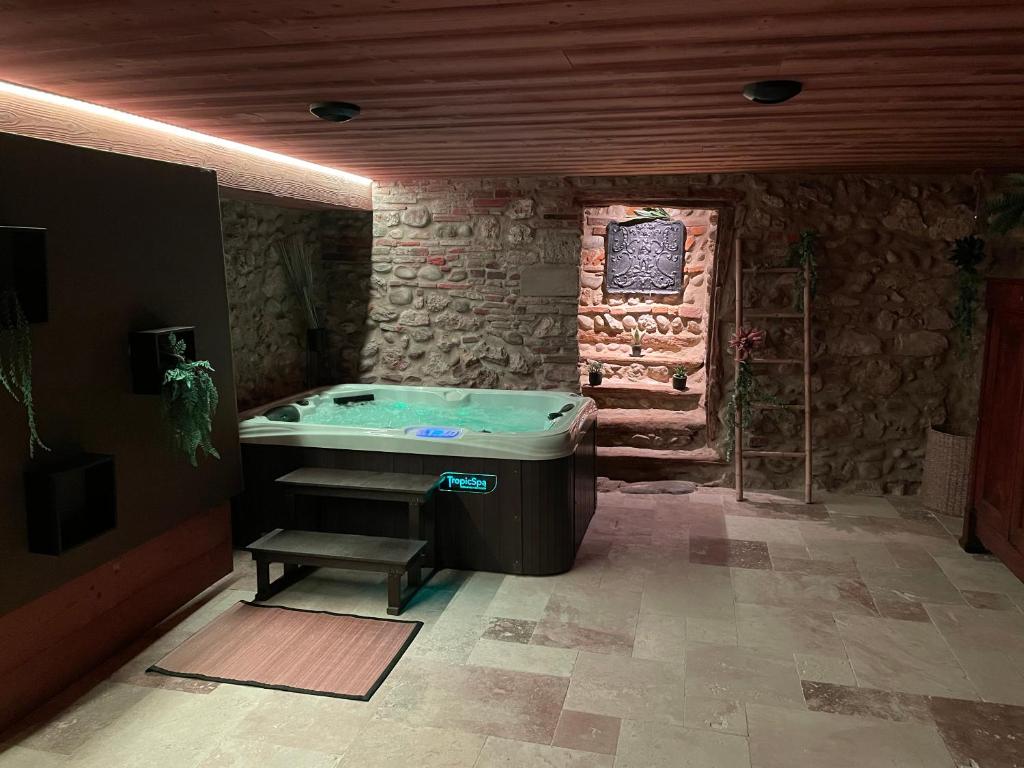 a bath tub in a room with a stone wall at Maison Pérouges spa in Pérouges