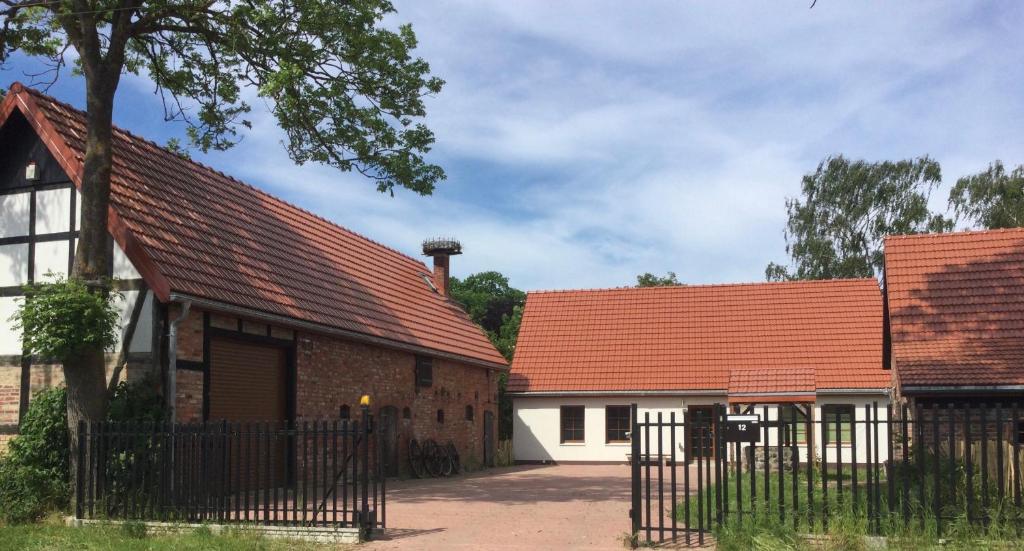 deux bâtiments avec des toits rouges et une clôture dans l'établissement Bauernhof am Storchennest mit Sauna und E-Tankstelle, à Chrzaszczewo