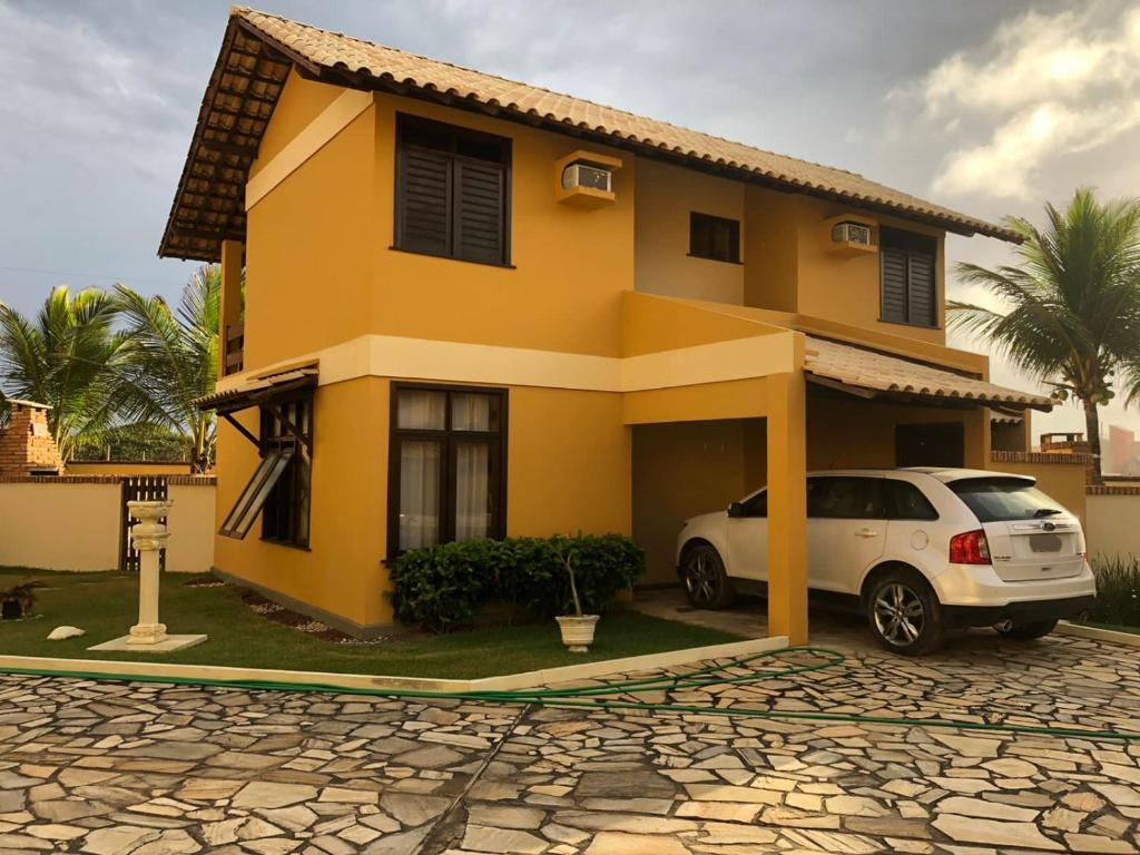 uma casa amarela com um carro estacionado em frente em Casa Conchas do Mar na Barra de São Miguel
