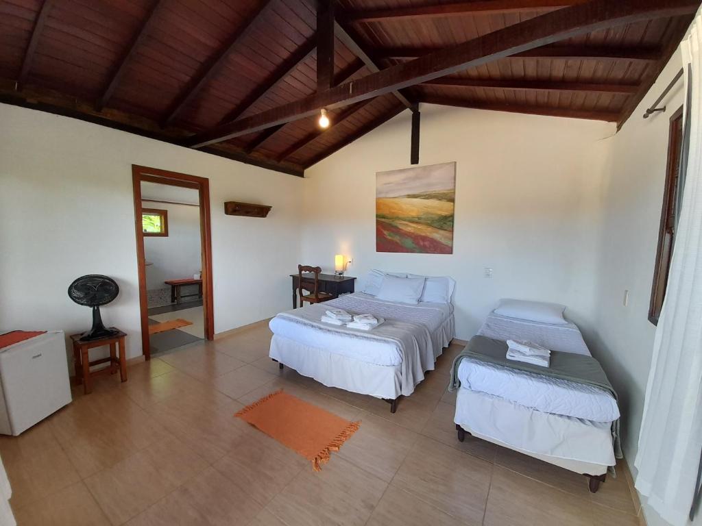 a bedroom with two beds and a table in it at Pousada Refazenda - Milho Verde in Milho Verde