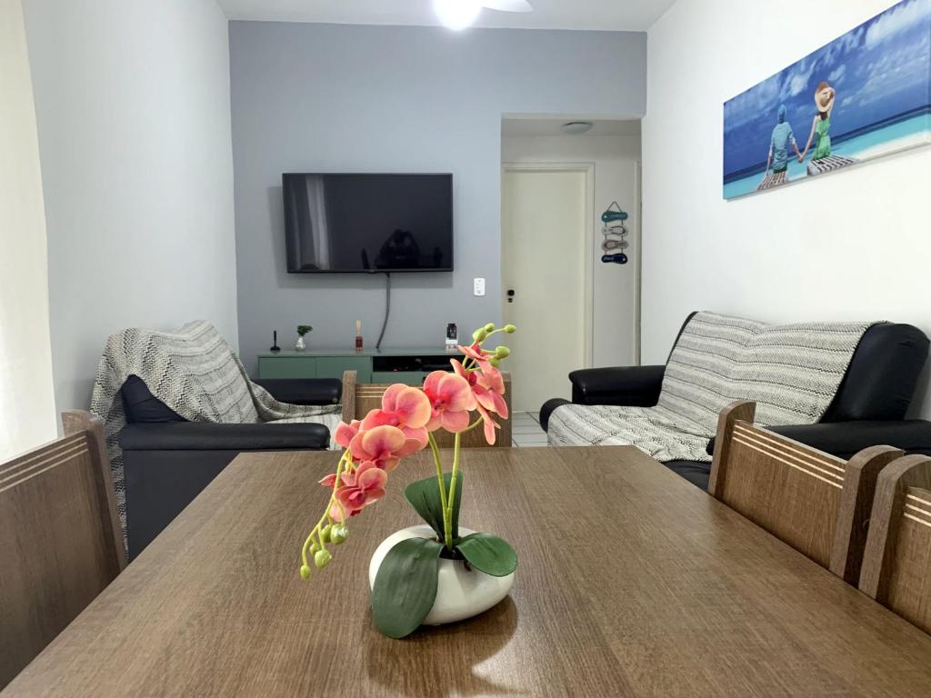 um vaso de flores numa mesa numa sala de estar em Apartamento aconchegante - Enseada - Guarujá no Guarujá