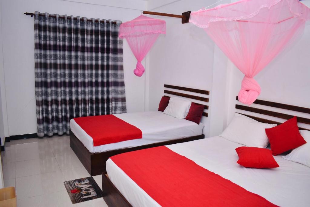 Geethani Tourists Home في بولوناروا: سريرين في غرفة حمراء وبيضاء