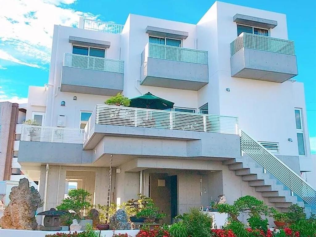 a white building with stairs and balconies on it at Room Biotop YOMITAN in Yomitan