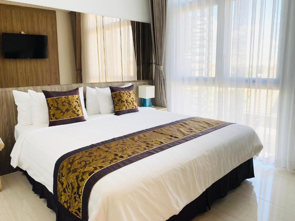 1 dormitorio con 1 cama grande con sábanas y almohadas blancas en Aurora Western Village en Ho Chi Minh