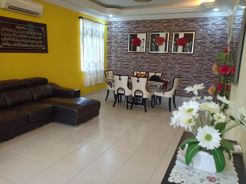 a living room with a couch and a table and chairs at Mutiara Desaru Cottage in Bandar Penawar