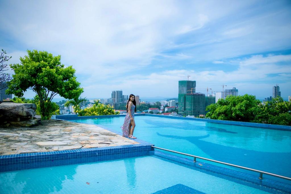 a woman standing on the edge of a swimming pool at 360 Resort in Sihanoukville