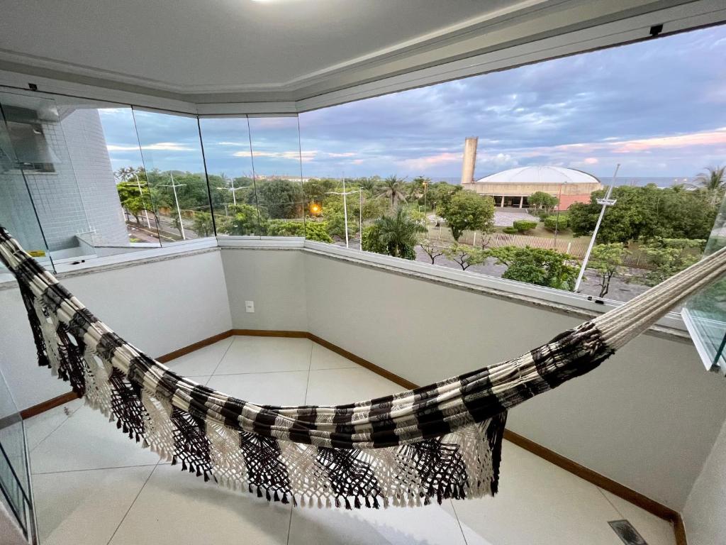 a hammock in a room with a large window at 3 SUITES Vista Mar - WI-FI, PISCINA, SAUNA, ACADEMIA, GARAGEM 2 CARROS in Ilhéus