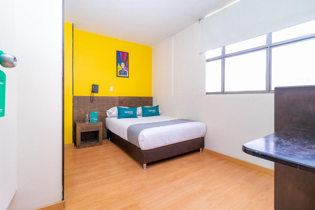 - une chambre avec un lit et un mur jaune dans l'établissement Ayenda Bochica, à Tunja