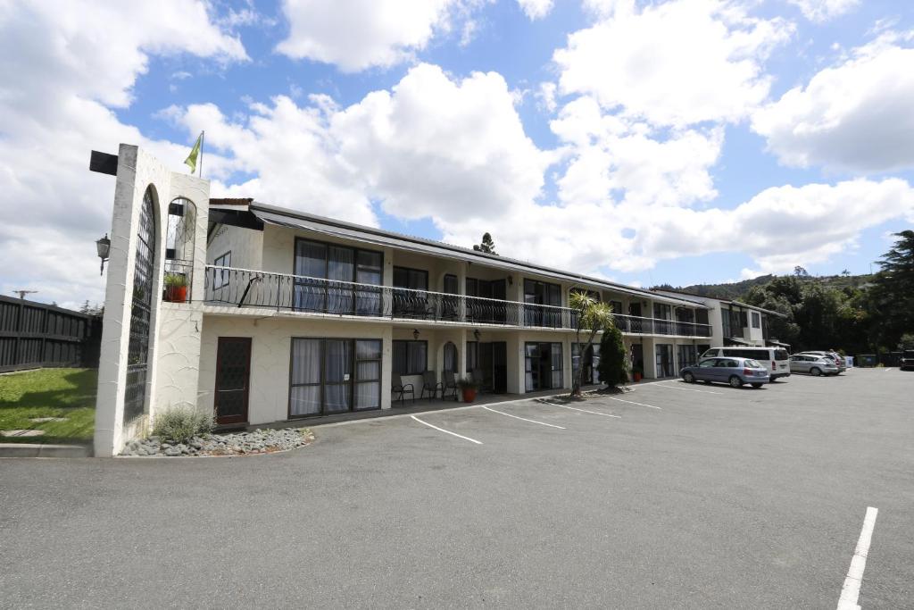 een gebouw met auto's geparkeerd op een parkeerplaats bij Motel Villa Del Rio in Whangarei