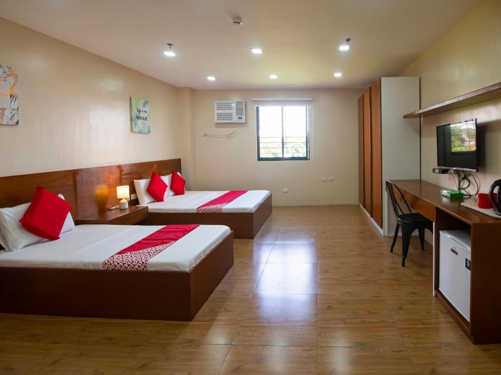 a hotel room with two beds and a desk at Super OYO 832 The Teepee Place Hostel & Residence Inn in Cebu City