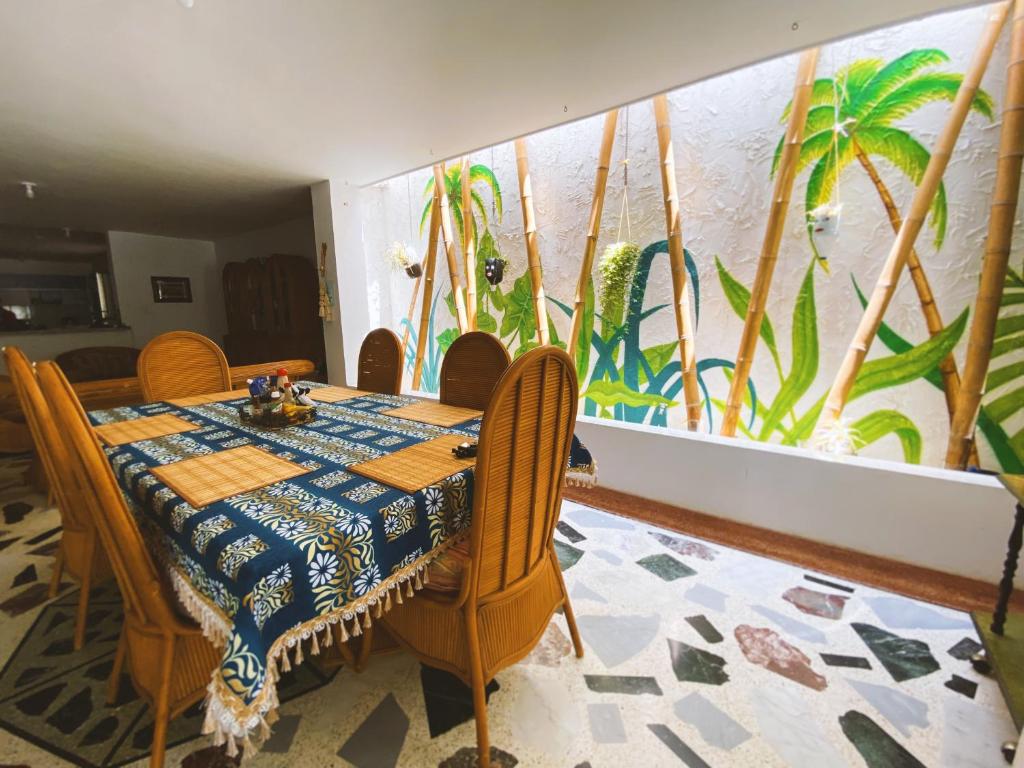 jadalnia ze stołem i krzesłami oraz malowidłem ściennym w obiekcie Tia Chela hostel w mieście Santa Marta