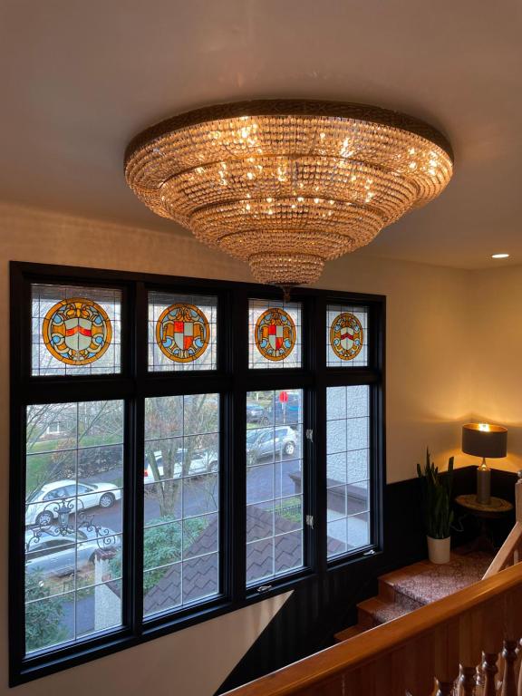 a large chandelier hangs over a staircase with windows at Cecil Bacon Manor in Seattle