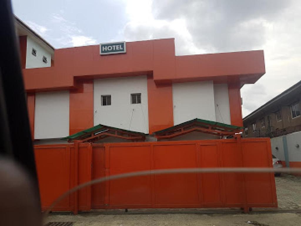 an orange and white building behind a fence at Room in Lodge - Prince Of Anthony 1960 Hotel-apartment in Lagos