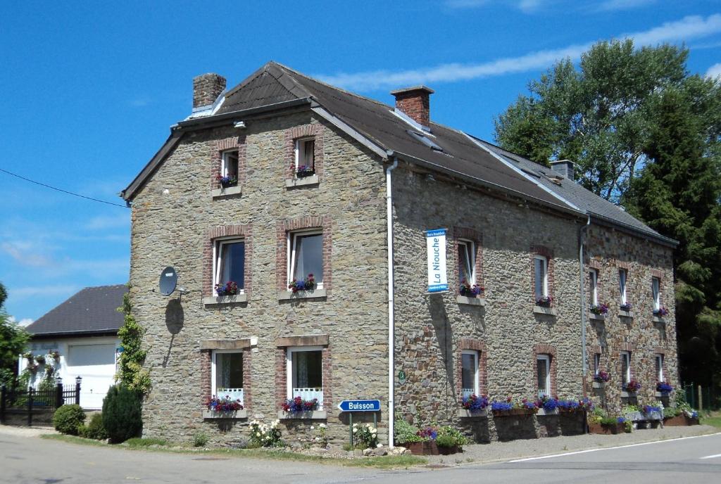 a large brick building with flowers in the windows at B&B La Niouche in La Roche-en-Ardenne