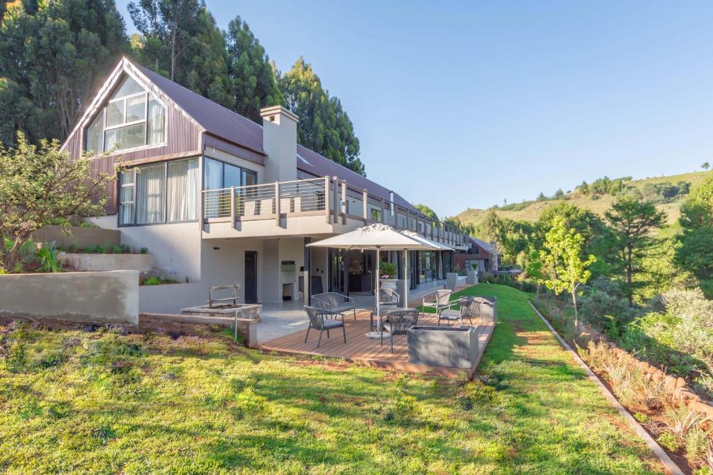 a house on a hill with a deck and a patio at Misty Meadows in Dullstroom