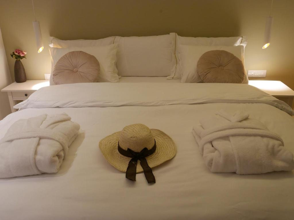 Una cama blanca con sombrero y toallas. en Mikiway סוויטה פנורמית בגלבוע, en Bet HaShitta