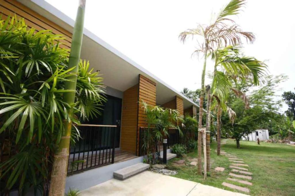 a house with palm trees in front of it at Phumi Resort in Thalang