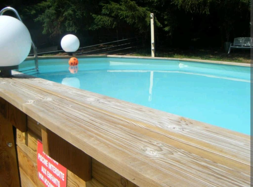 a swimming pool with two balls on top of it at LA PARENTHÈSE AU PAYS DU VERT in Soucht