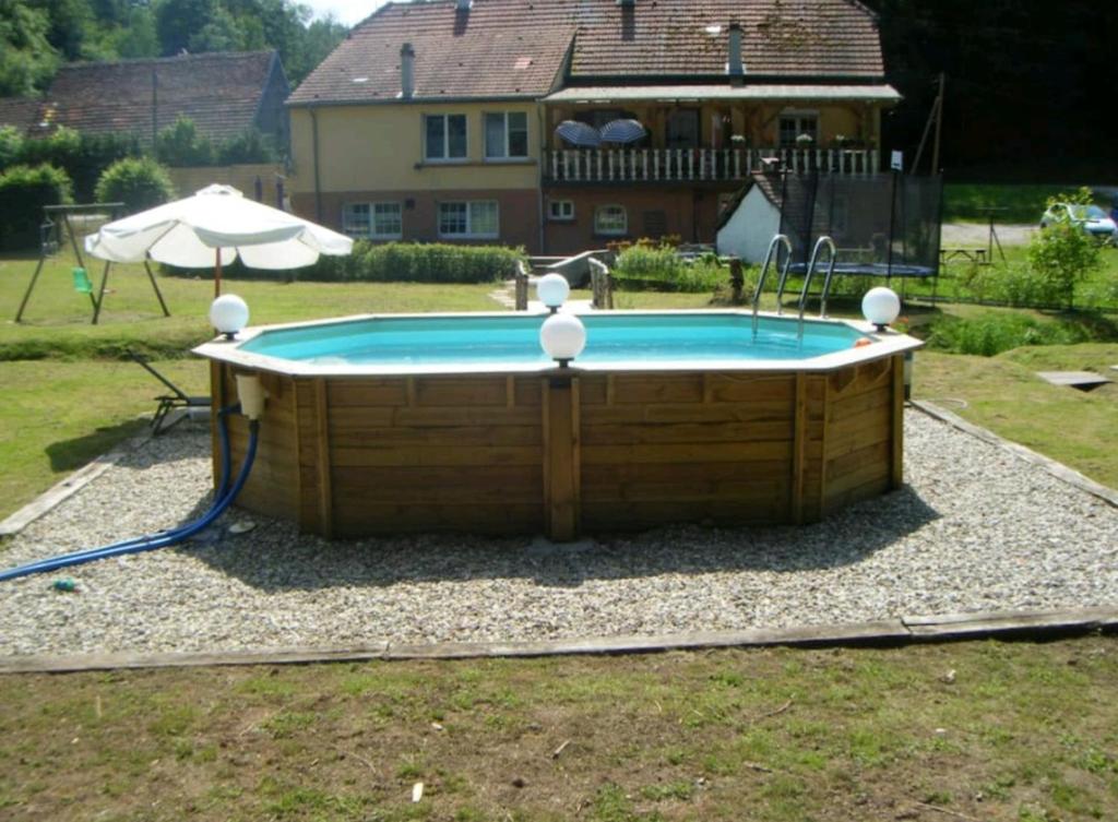 a pool with a table and an umbrella in a yard at LA PARENTHÈSE AU PAYS DU VERT in Soucht