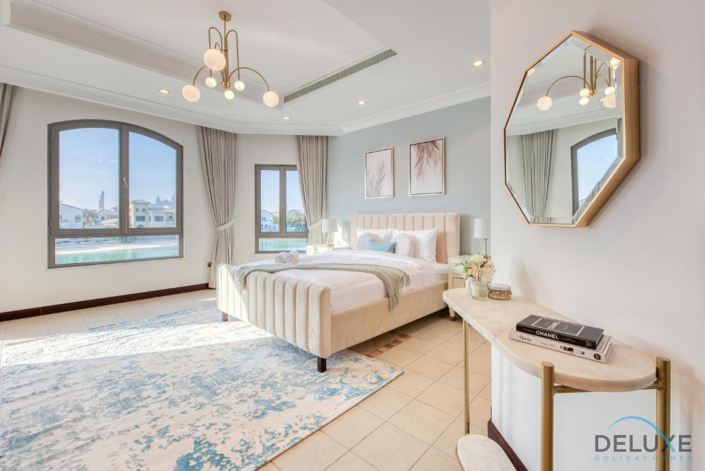 a bedroom with a bed and a mirror and a table at Breath-taking 5BR Villa with Assistants Room and Private Pool in Frond E Palm Jumeirah by Deluxe Holiday Homes in Dubai