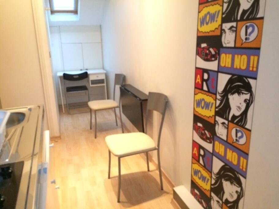 a room with two stools and a kitchen with a wall at Studio centre-ville climatisé avec parking gratuit in Clermont-Ferrand