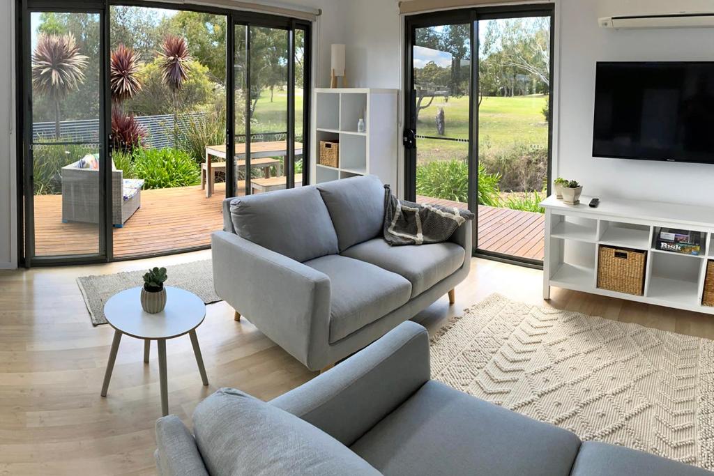 un salon avec un canapé et une télévision dans l'établissement Fairways 1, à Coles Bay