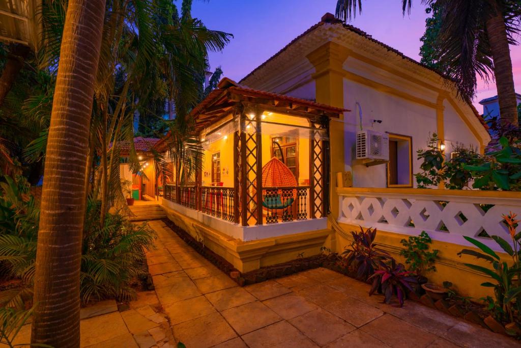 a house with a balcony and a palm tree at goSTOPS Goa, Calangute in Calangute