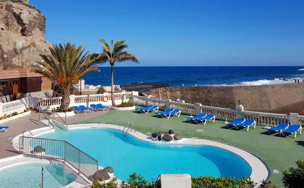 una piscina con sillas y el océano en el fondo en Maravillosa vivienda con piscina al lado del mar en La Estrella