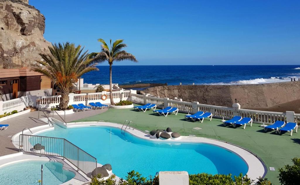 a pool with chairs and the ocean in the background at Maravillosa vivienda con piscina al lado del mar in La Estrella