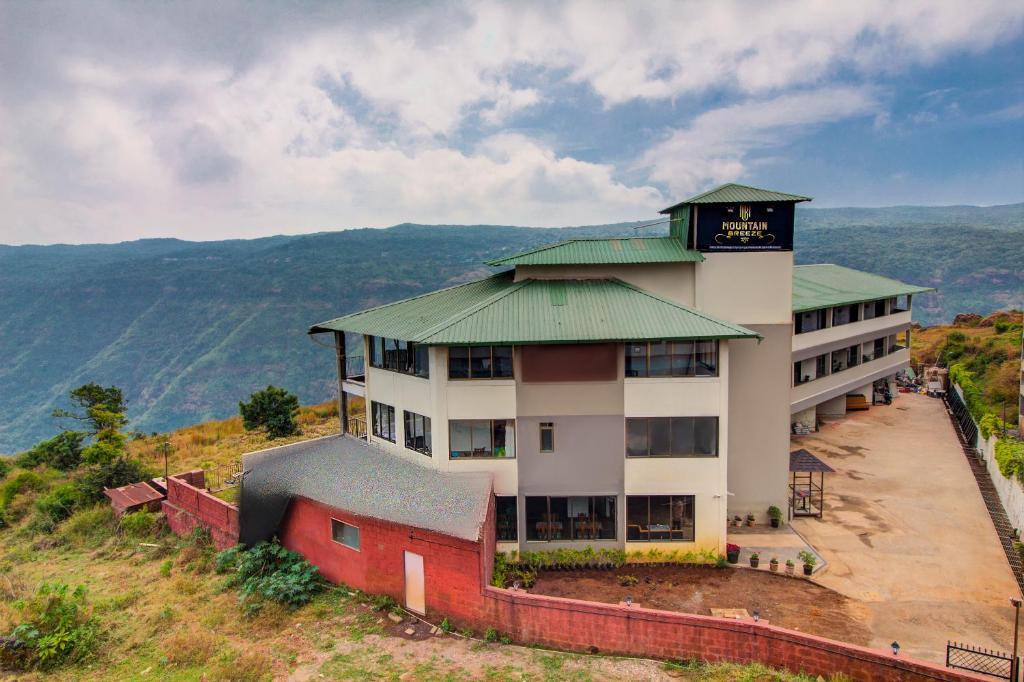 a building with a clock on the top of a hill at Mountain Breeze Resort, Mahabaleshwar in Mahabaleshwar