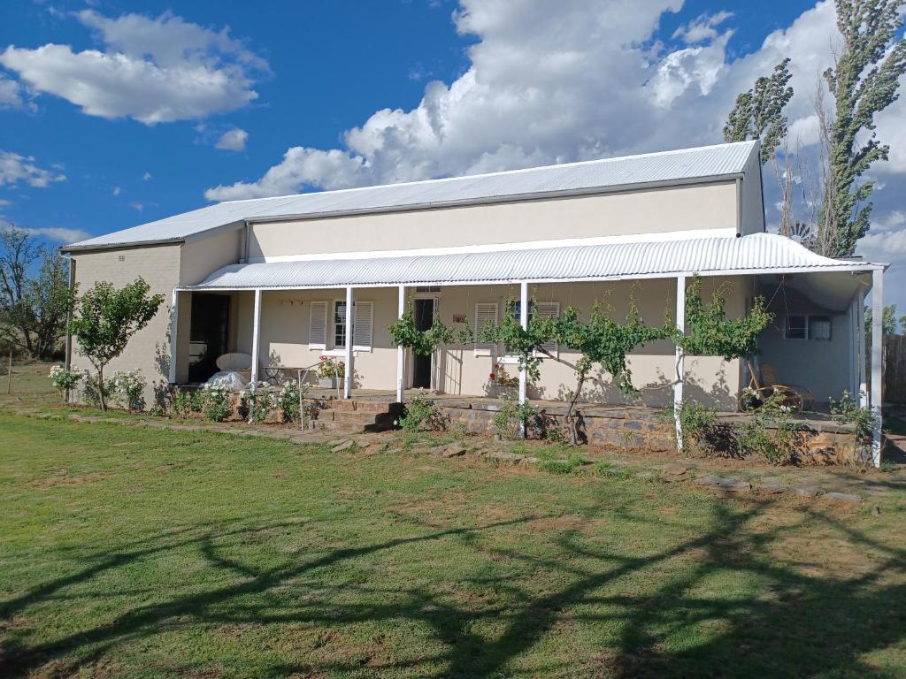 a white house with a yard in front of it at Yardley Cottage in Colesberg