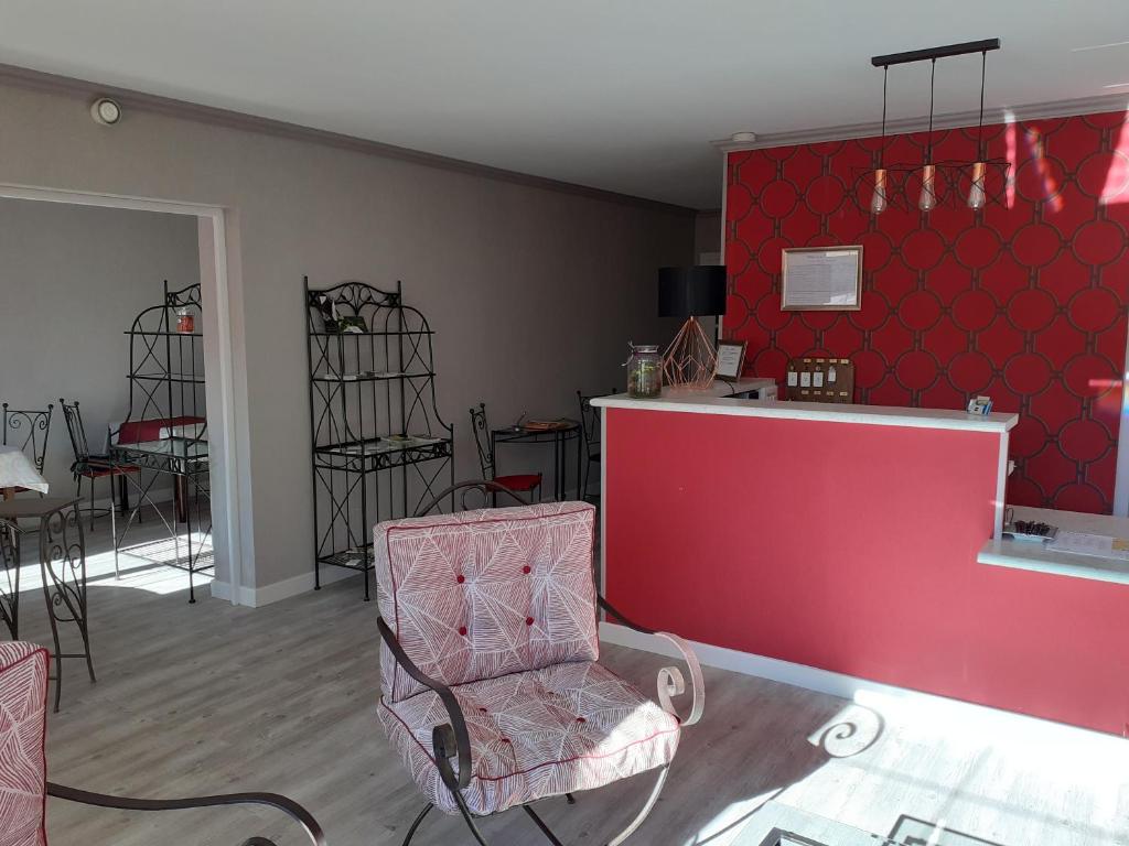 a living room with a red wall and a chair at Hôtel de la Poste in Chagny