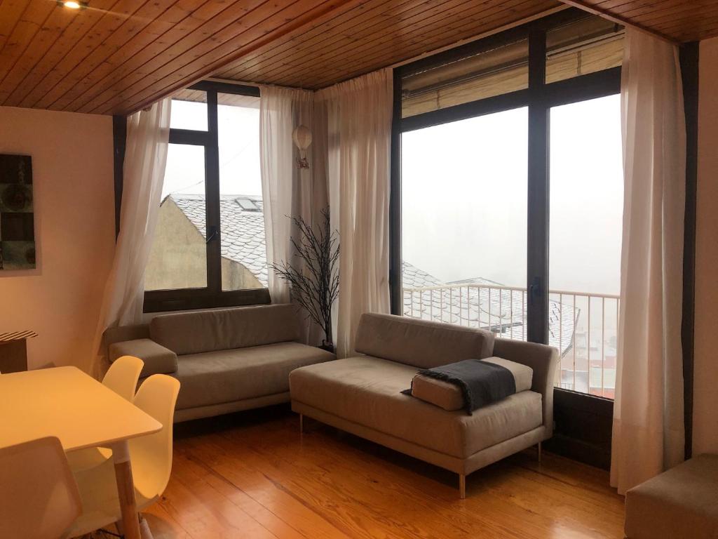 ein Wohnzimmer mit einem Sofa, einem Tisch und Fenstern in der Unterkunft Apartamento en Puigcerda in Puigcerdà