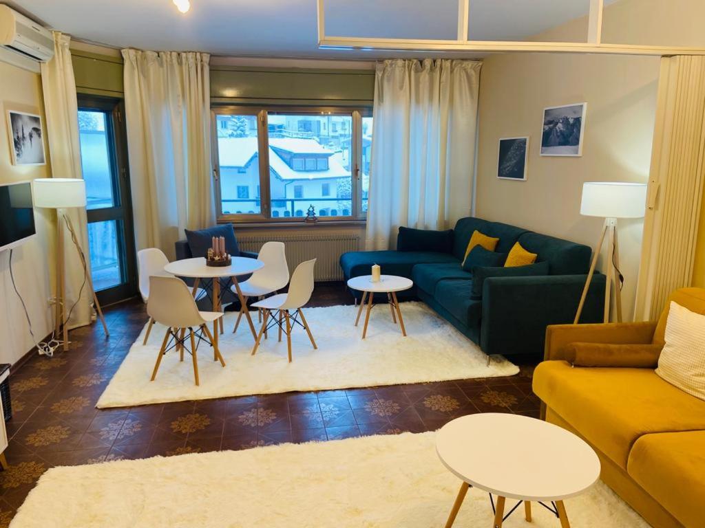 sala de estar con sofá, mesas y sillas en Alpský apartmán Zoncolan, en Ravascletto