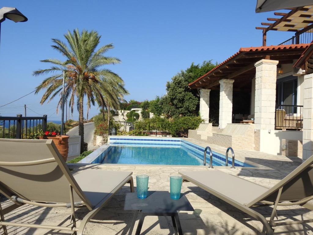 - une piscine avec 2 chaises et une table à côté d'une maison dans l'établissement Villa Marianne, à La Canée