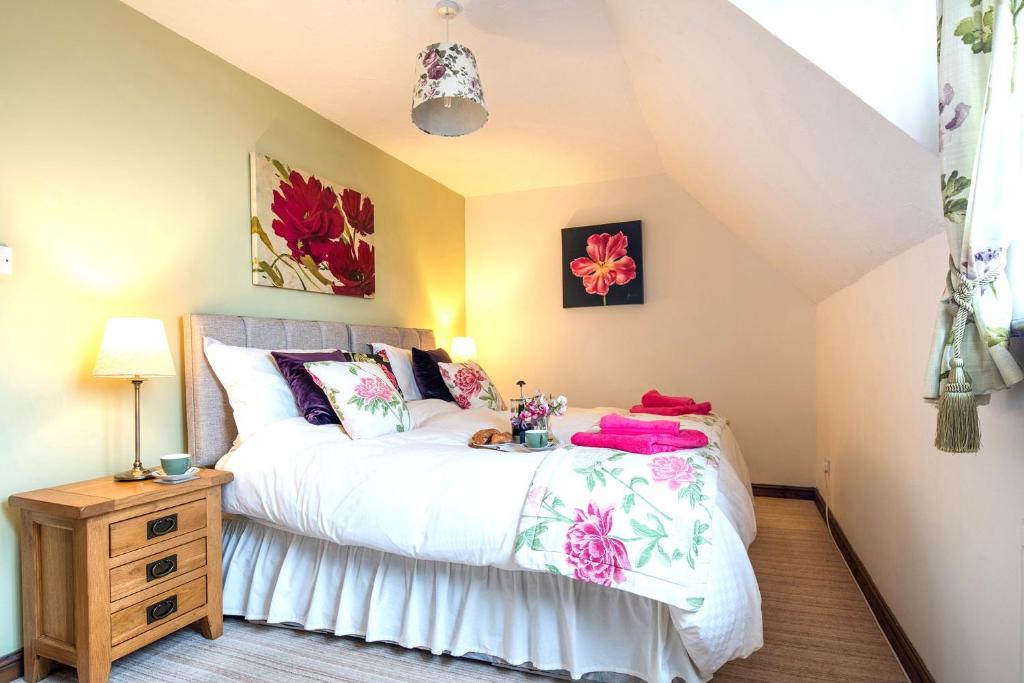 ein Schlafzimmer mit einem Bett mit weißer Bettwäsche und Blumen in der Unterkunft Charming Cottage near Cartmel with free Spa access in Holker